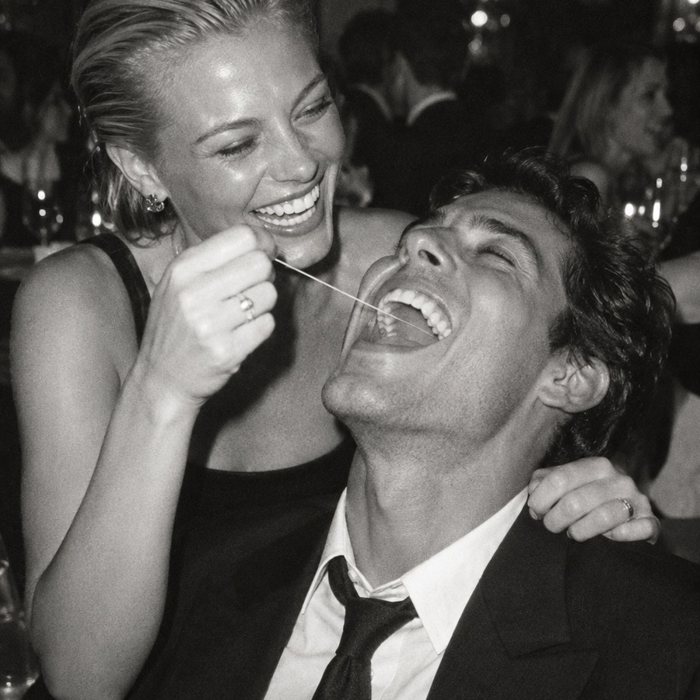 A woman flosses a laughing man's teeth at a party